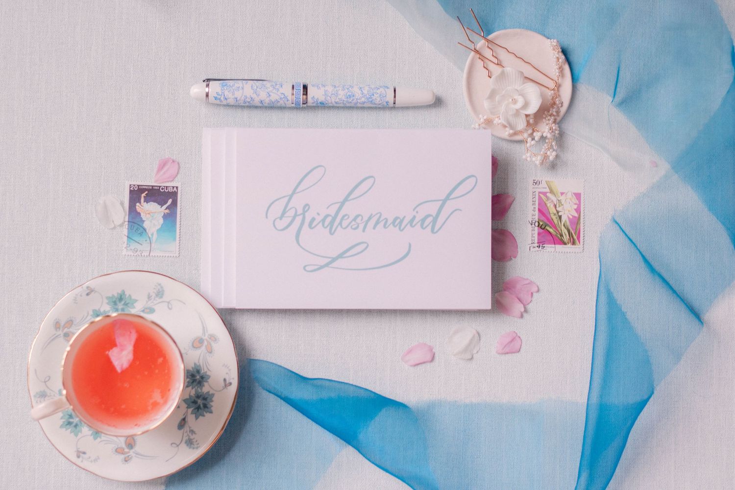 Wedding stationery and decor items arranged on light blue tulle fabric background.
