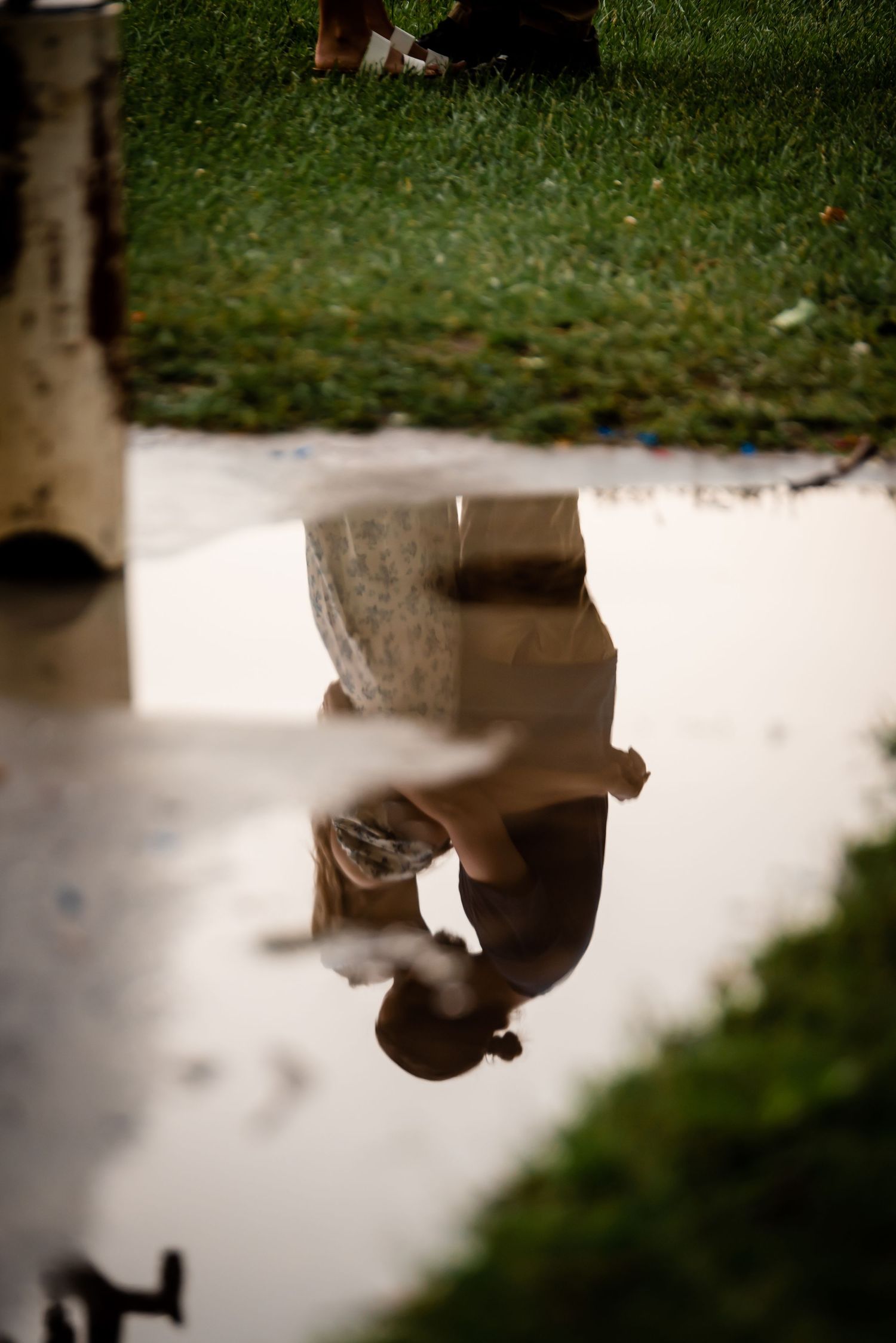 Creative reflection shot in a puddle showing an inverted silhouette against trees and grass.