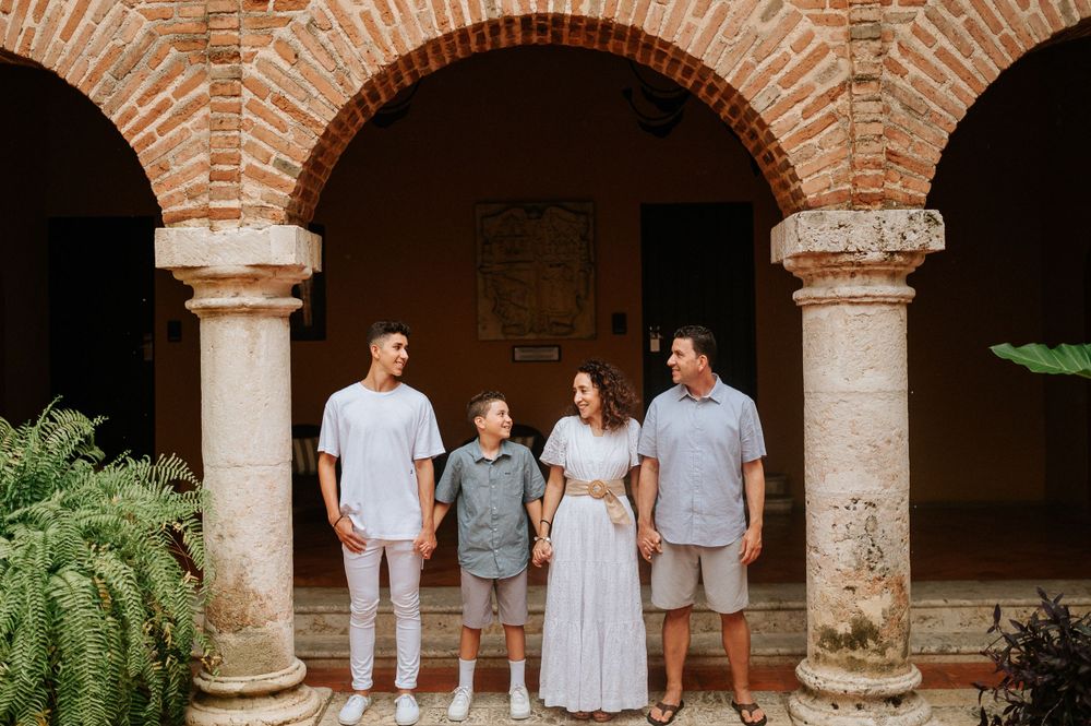 Family poses together under classic brick archways with terracotta walls and greenery.