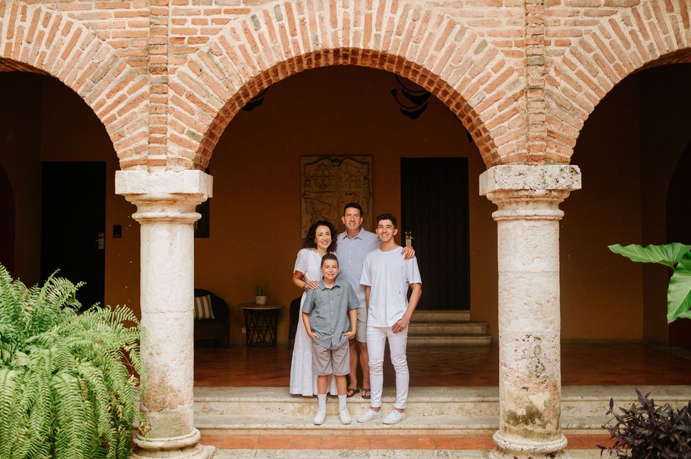 Family portrait under ornate brick archways with classic columns and lush greenery.