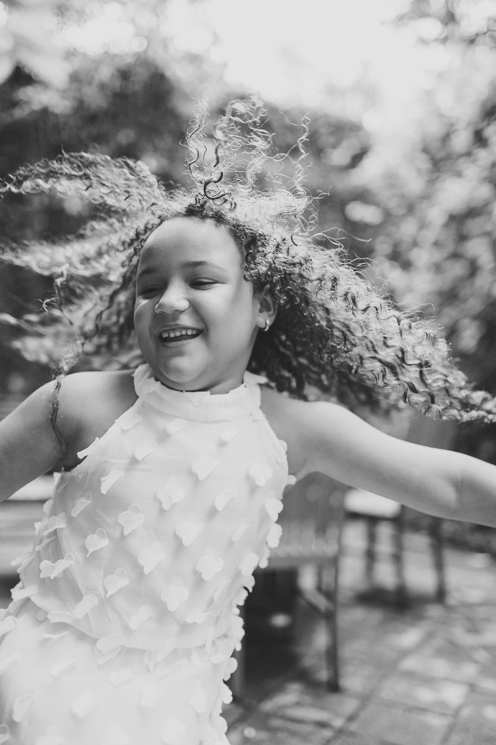 Dynamic black and white photo of someone spinning with curly hair flying in the breeze.
