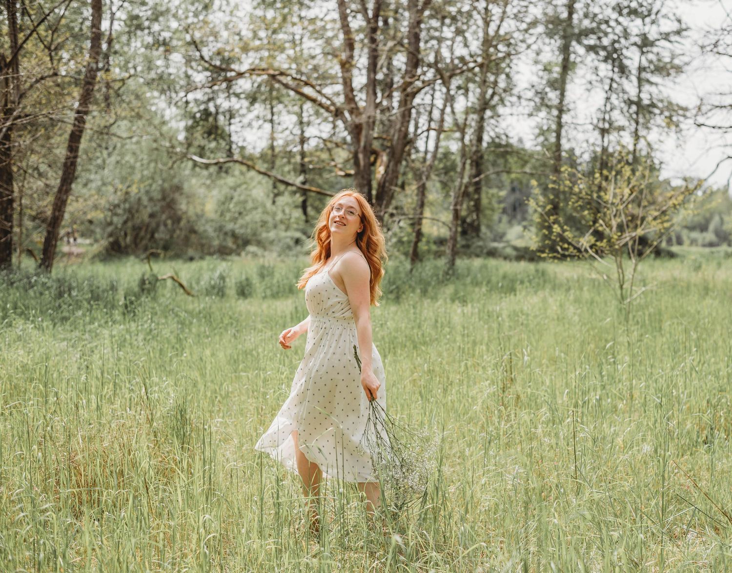Natural outdoor setting with green grass and scattered trees on a bright day.