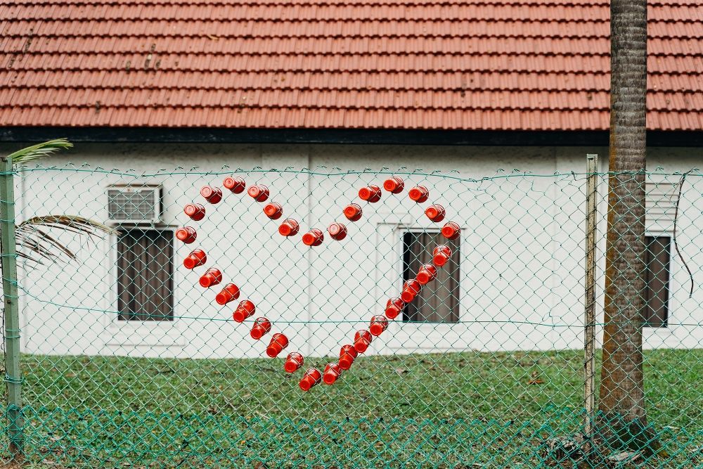A heart made of red drink cups has been made on a wire fence