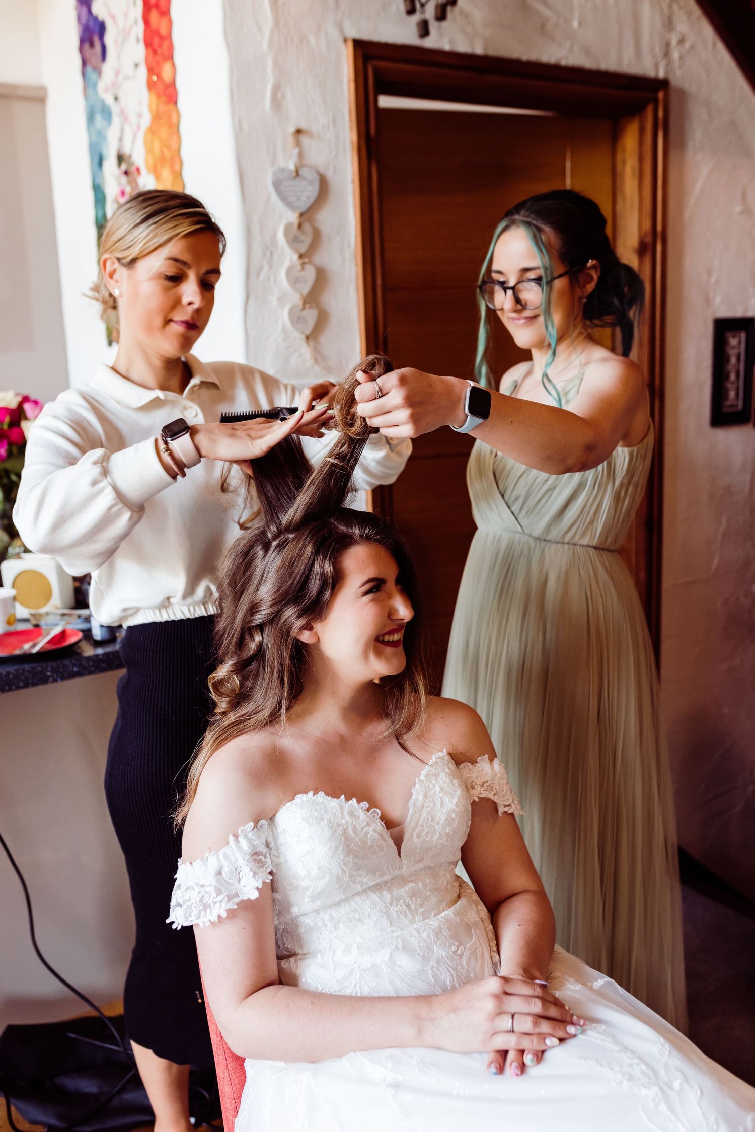Wedding preparation scene with styling of hair while wearing elegant white gown.