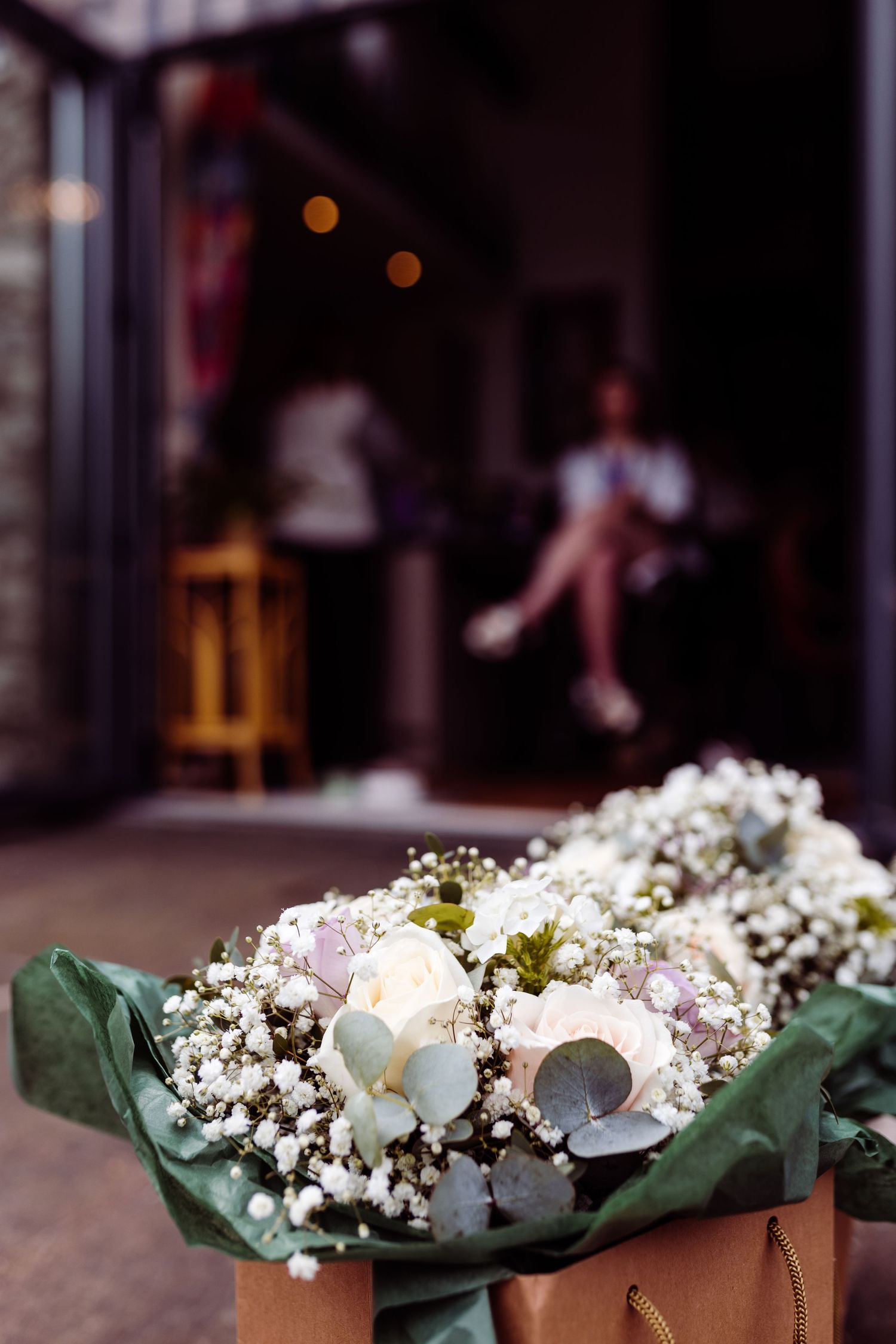 Wedding bouquet with white flowers and baby's breath wrapped in green paper.