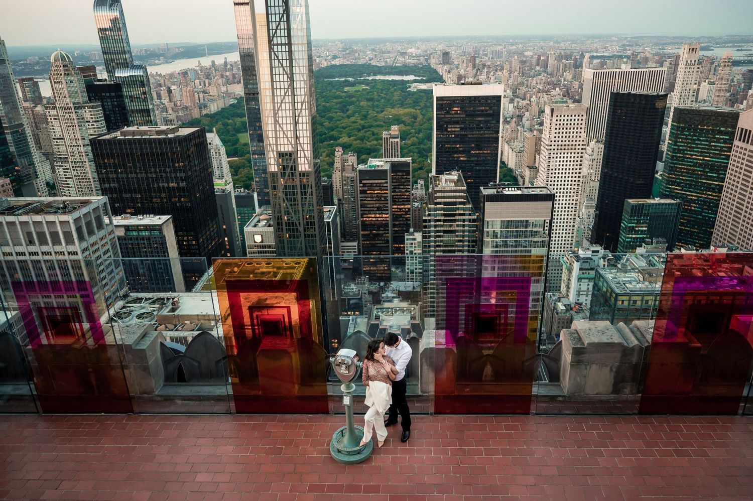 Panoramic cityscape view from a modern skyscraper observation deck showing urban buildings and skyline.