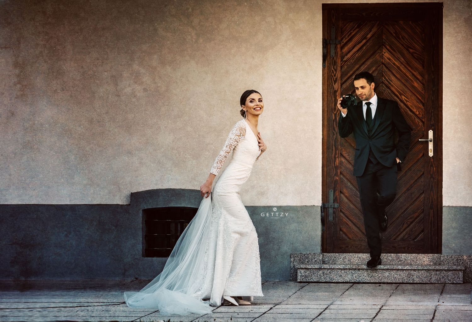 Elegant wedding scene with beautiful white gown against rustic wooden door.