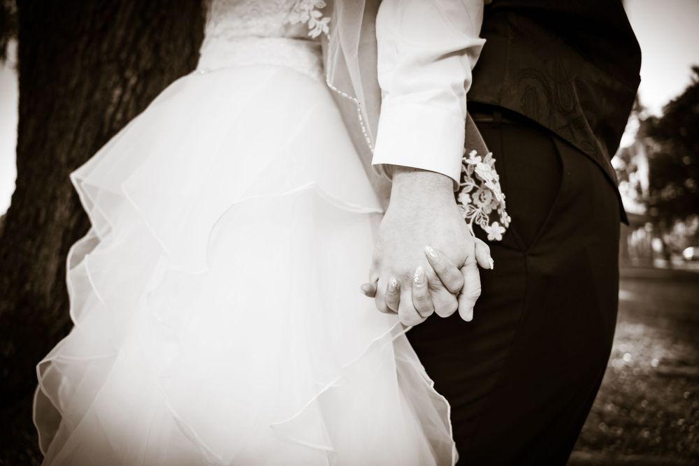 Close-up details of wedding attire and hands in an artistic black and white sequence.