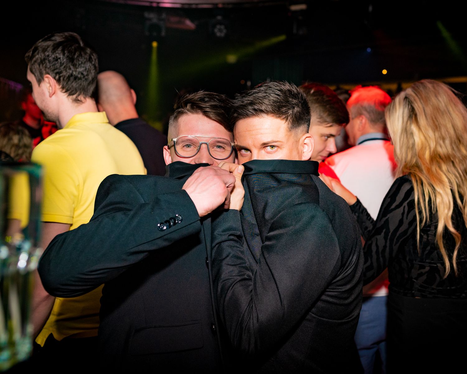 Partygoers in dark clothing enjoying a night out at a dimly lit club.