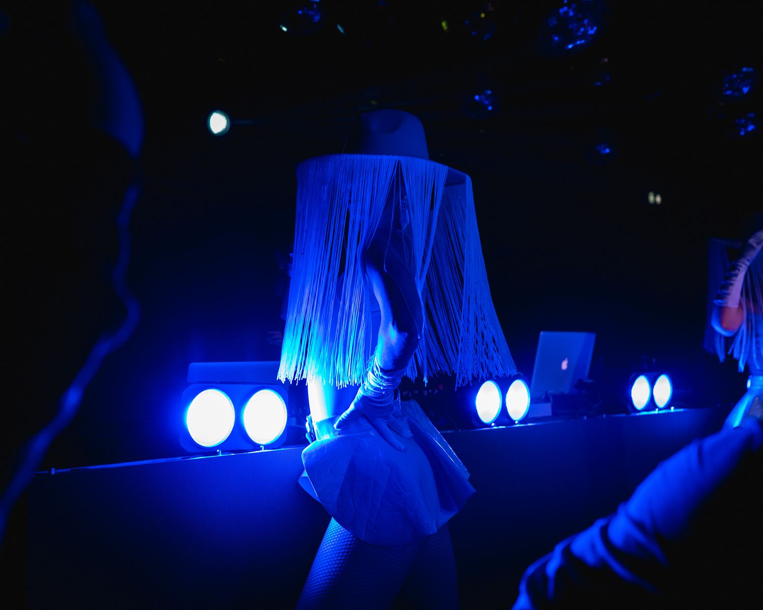 Club performer in silhouette against dramatic blue stage lighting.