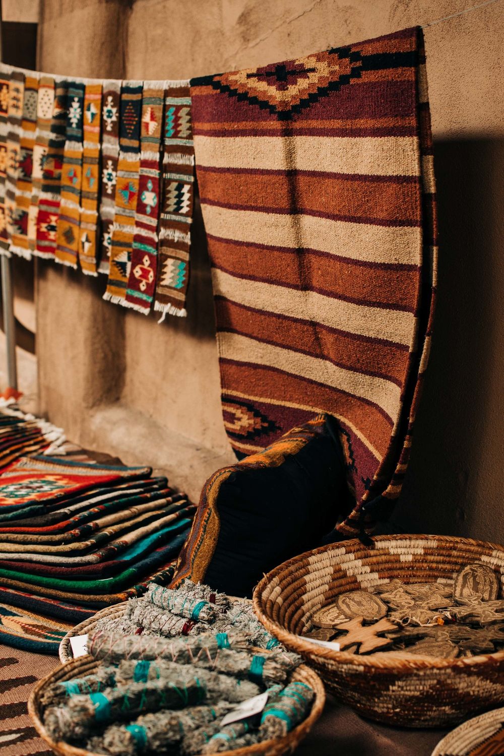 Display of handwoven Native American rugs and baskets with traditional patterns and turquoise accents.