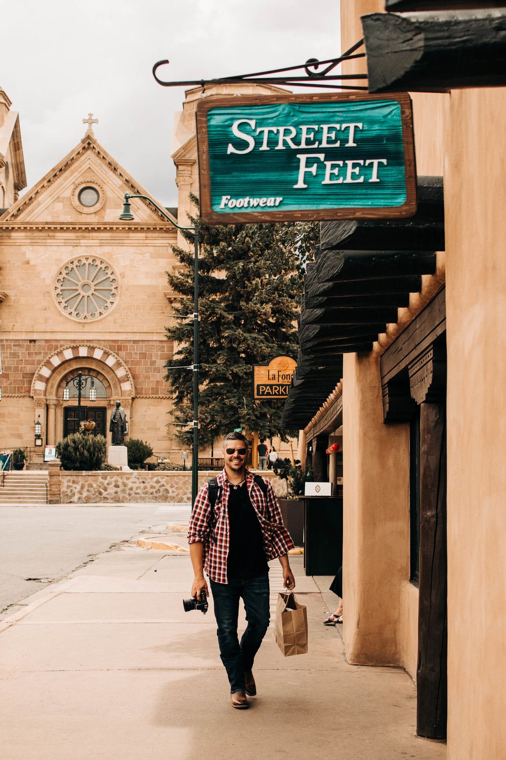 Street view of Santa Fe with adobe architecture and a green shop sign.