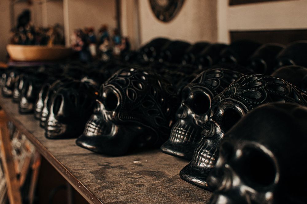 Collection of black decorative skull ornaments displayed on wooden shelving.