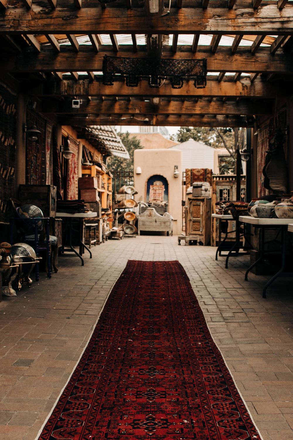 Long red Persian rug leading through an antique-filled hallway with wooden beams.