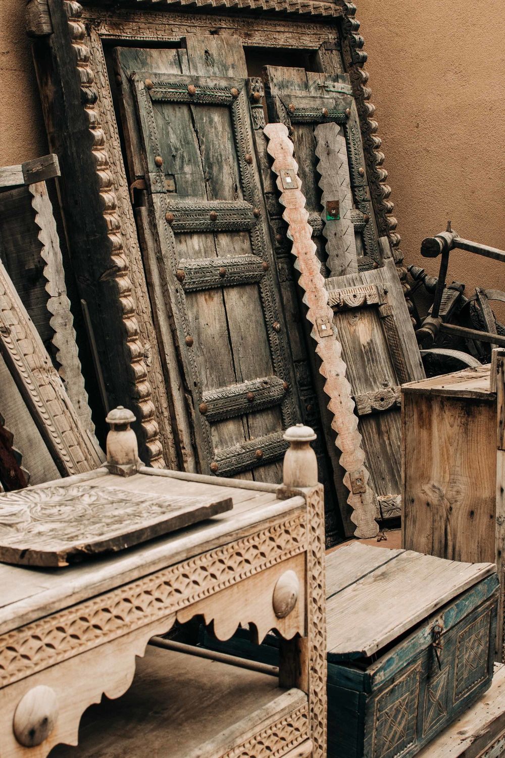 Antique wooden doors and furniture with ornate carved details in rustic style.