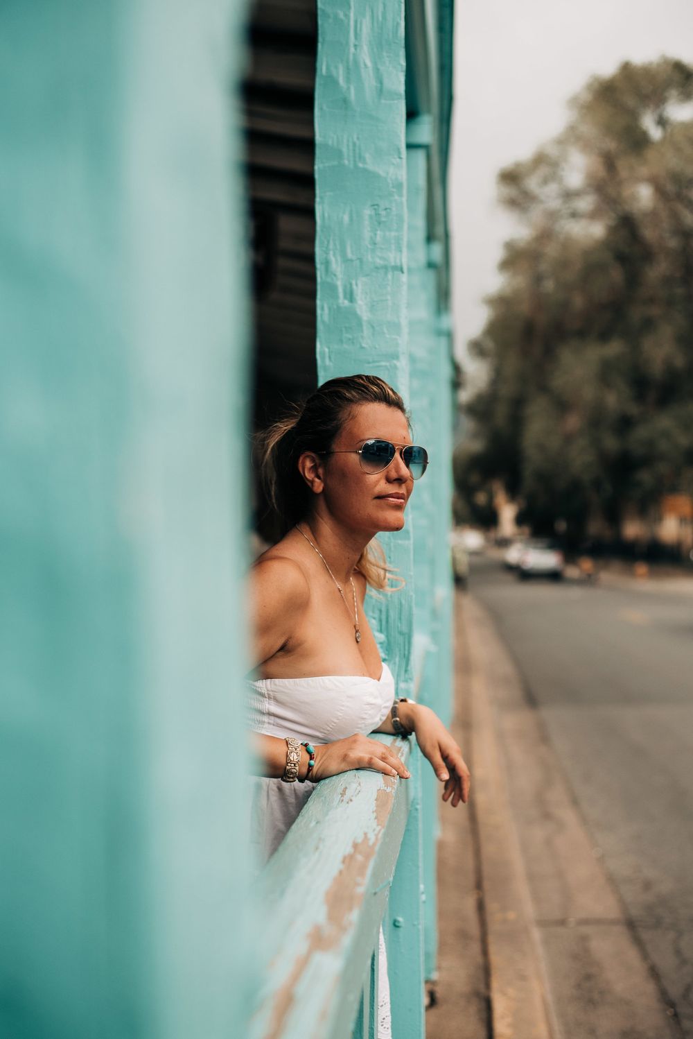 Artistic portrait against a turquoise wall in urban setting.