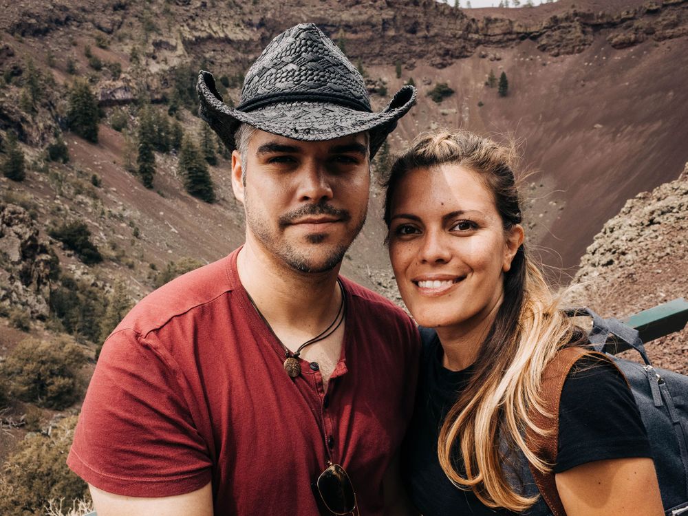Adventurous couple poses against backdrop of red desert canyon landscape.