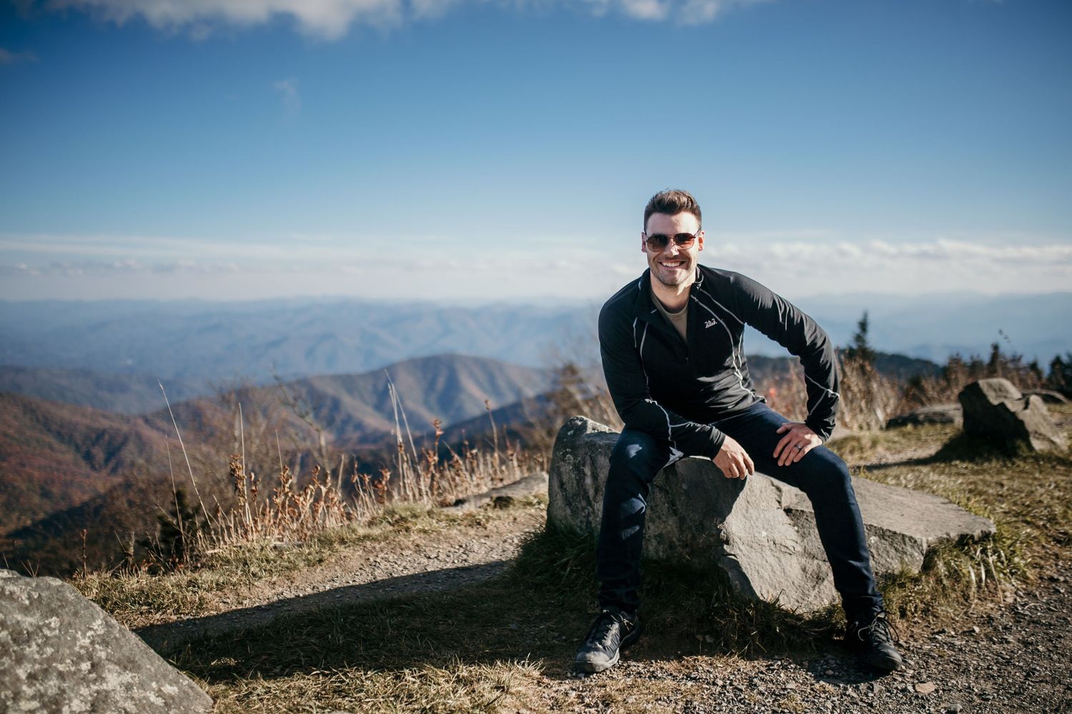 Handsome man wearing sunglasses on the top of a mountain