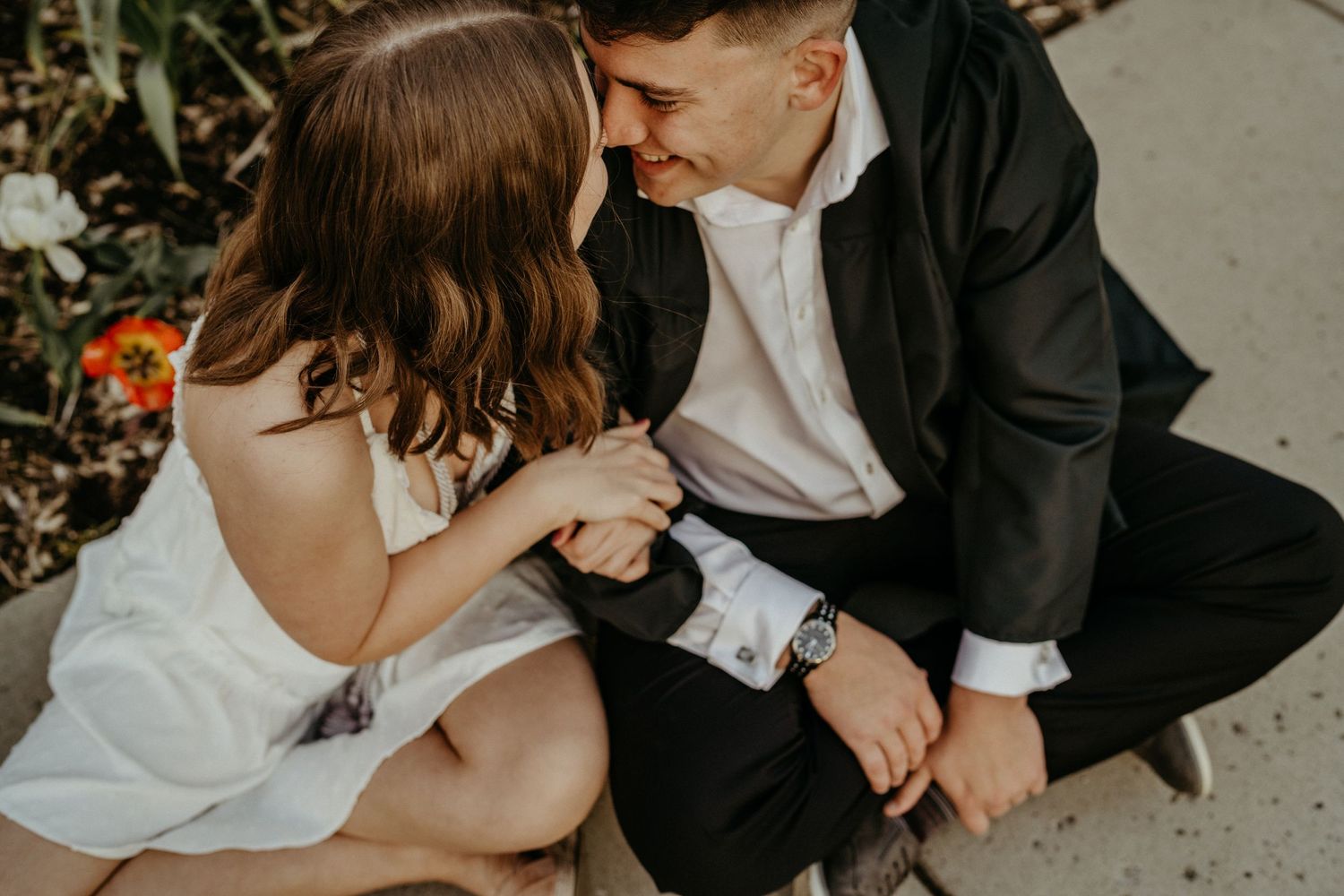 Intimate moment between couple sitting outdoors in formal attire.