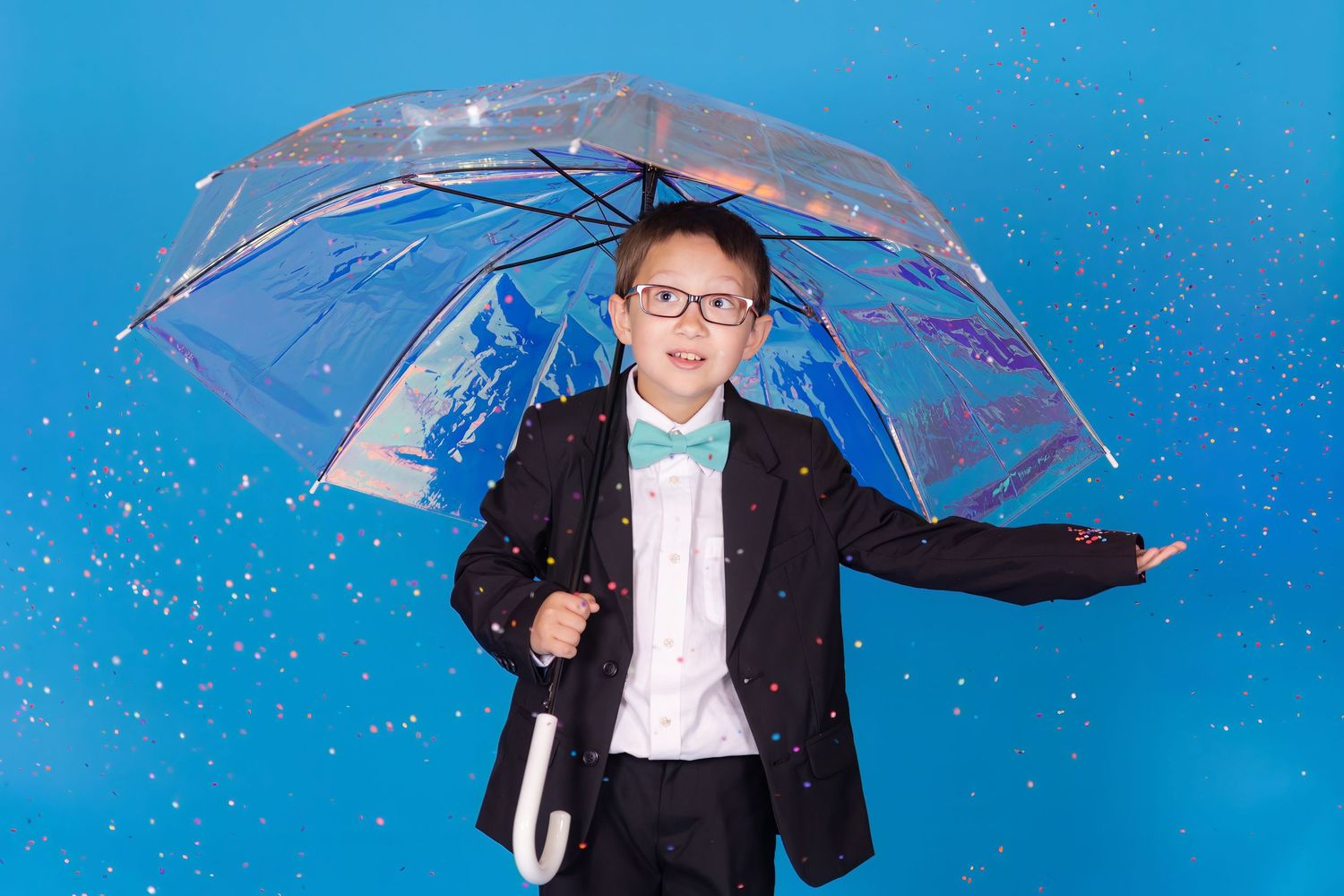 child holding irridescent umbrella on savage blue jay backdrop with confetti in studio in clayton new jersey Gloucester