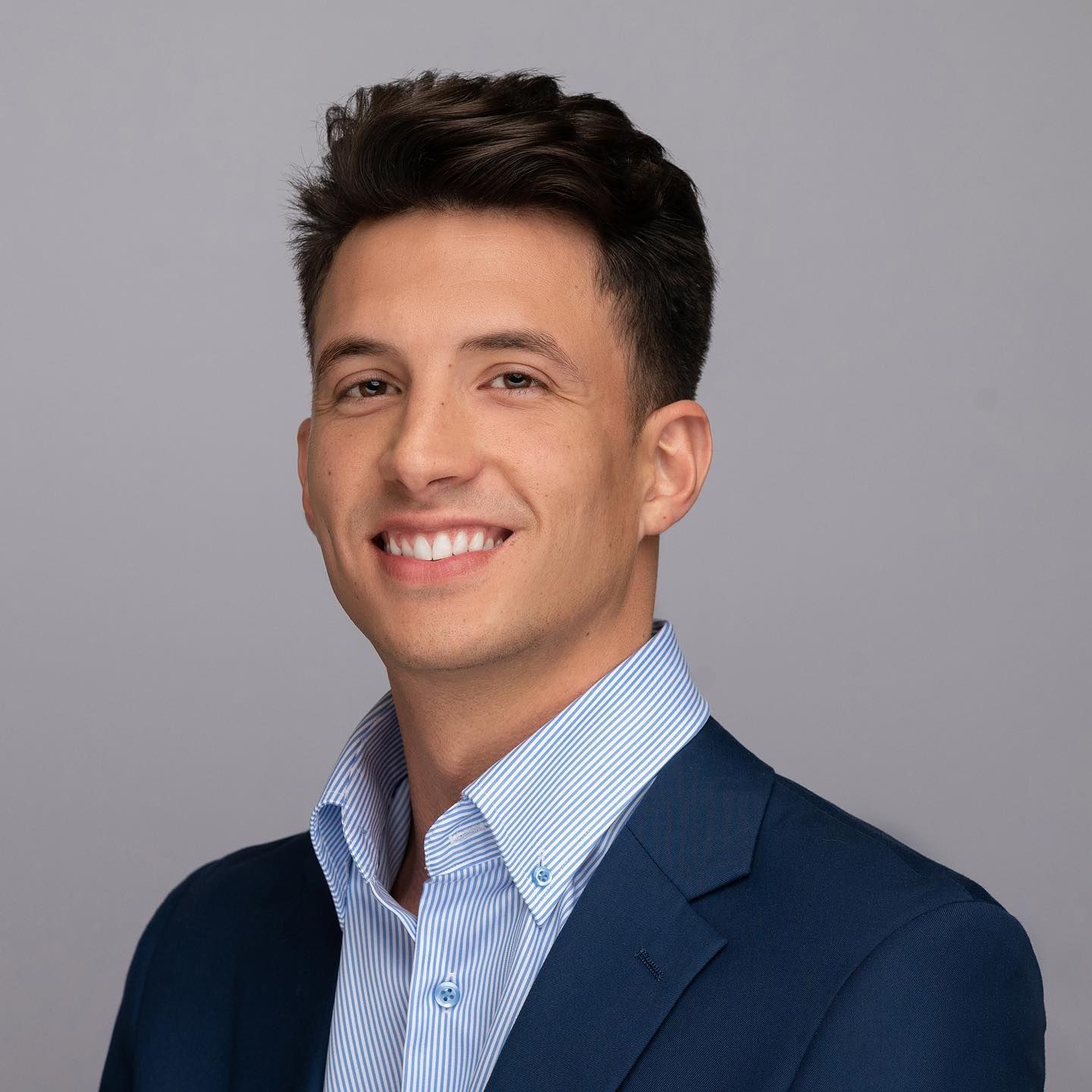 Orlando headshot photographer Ray Alvarez — young entrepreneur headshot in navy blazer with gray studio background