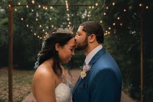 Groom kisses bride on forehead while sharing a private first dance under market lights