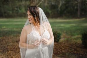 Bride stares off into the distance with a smile on her face as her hands clasp her veil