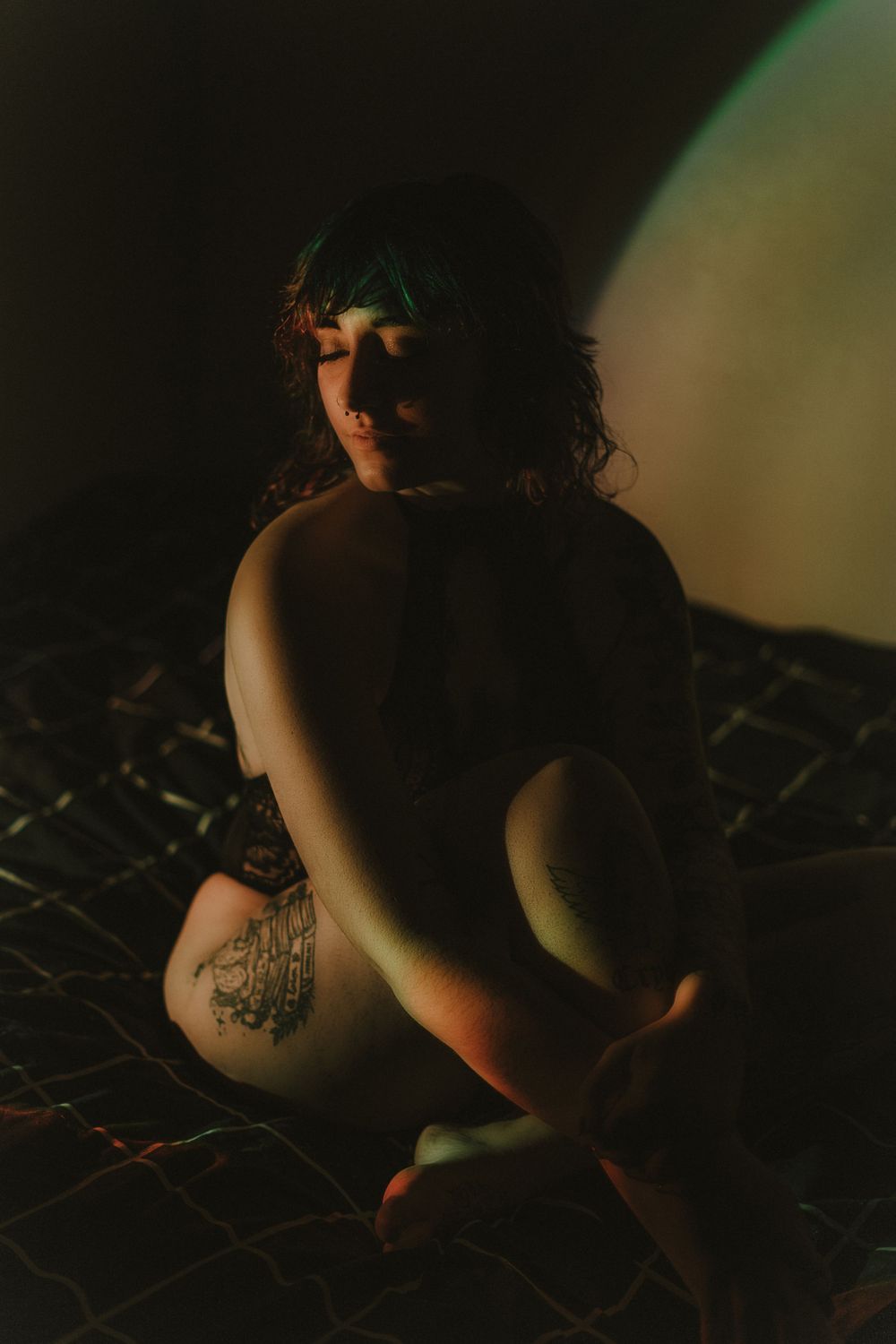 Artistic silhouette portrait with soft green ambient lighting in dark setting.