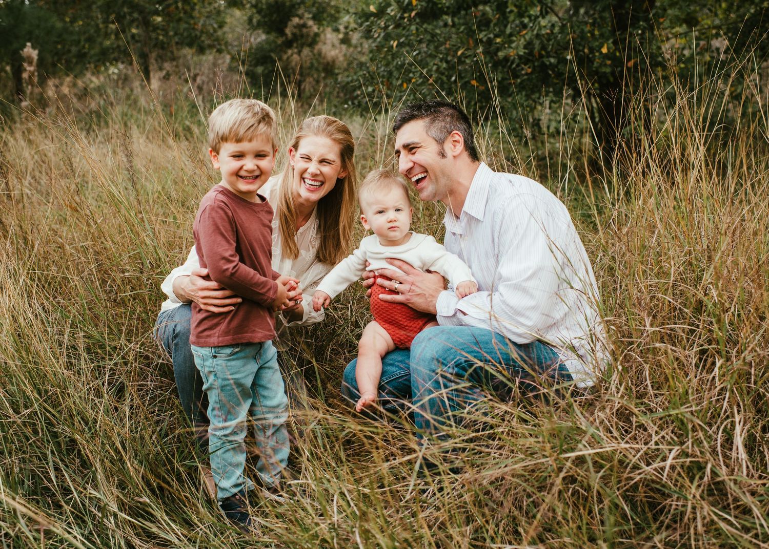 Family having fun together while lying in tall grass during an outdoor photo session.
