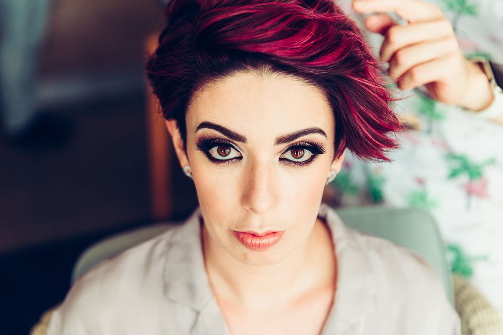 Portrait of person with vibrant red pixie haircut and dramatic makeup.