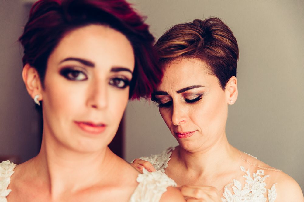 Close-up of two people with short hair styles wearing white lace dresses.