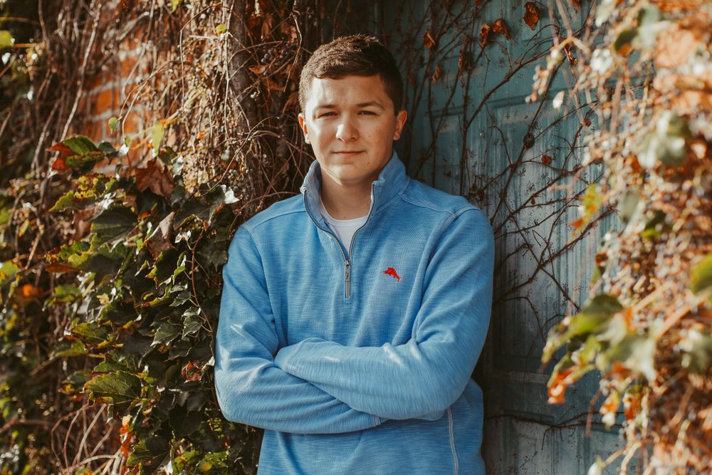 Portrait series against autumn foliage wearing light blue sweater.