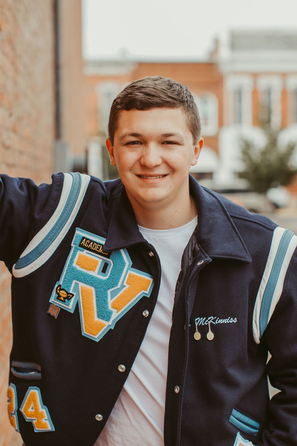 A varsity letterman jacket with teal and gold accents shown in close-up detail shots.