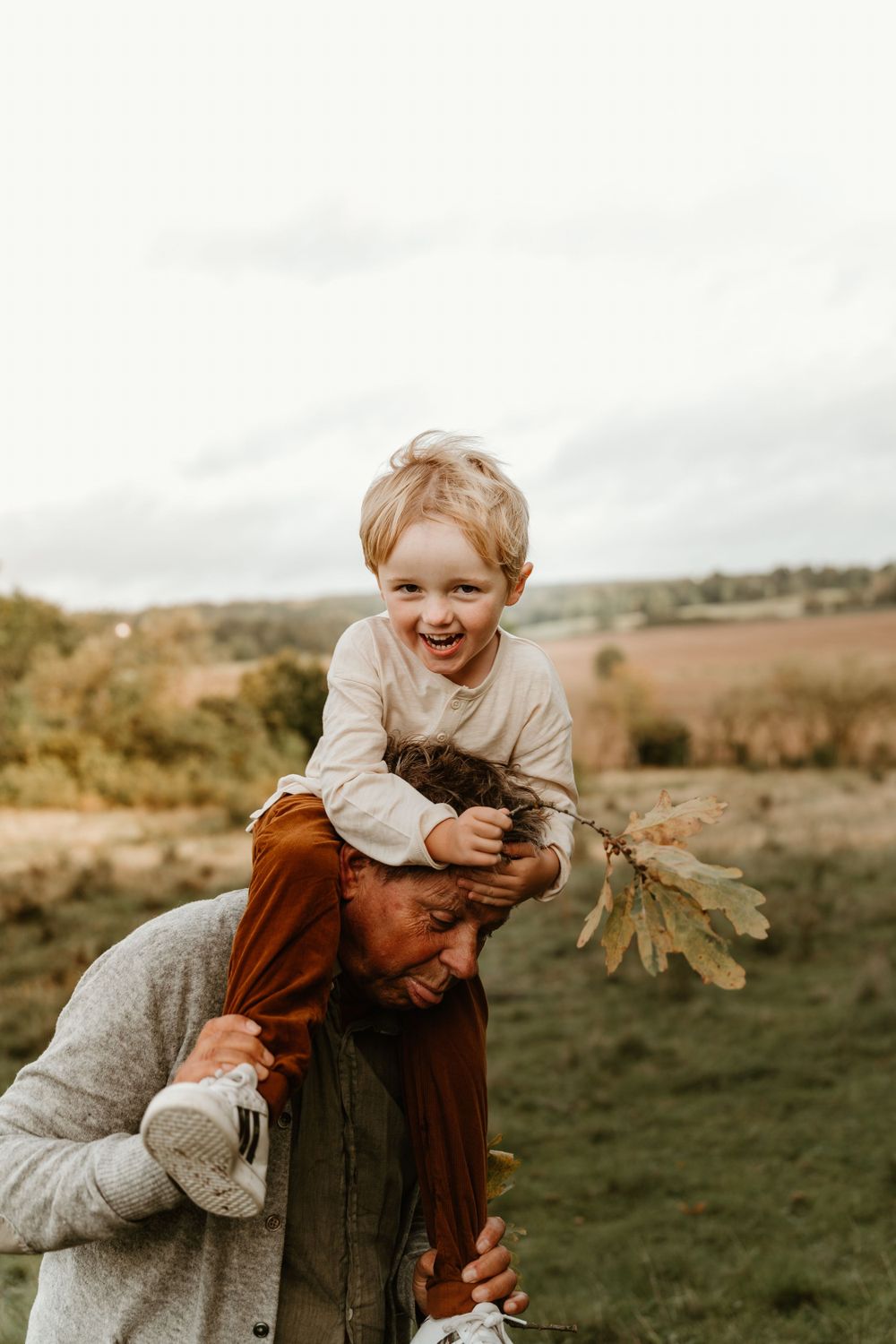 A playful piggyback ride moment captured in warm autumn light on a hillside.