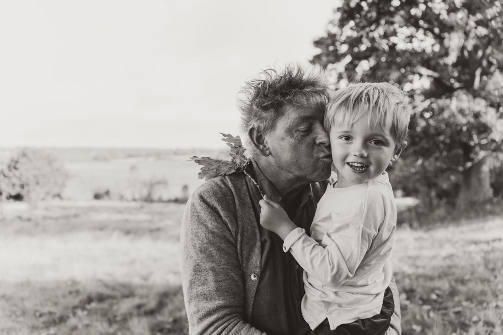 A tender black and white moment shared outdoors with rolling hills in the background.