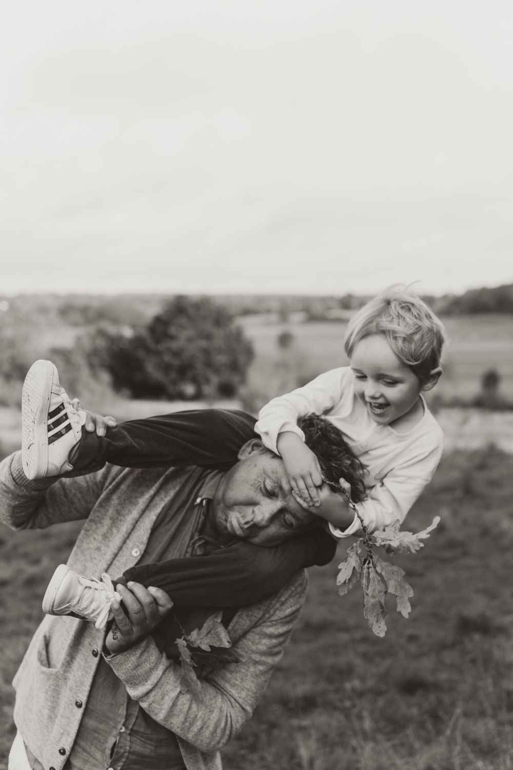 A black and white capture of playful outdoor interaction with autumn leaves.