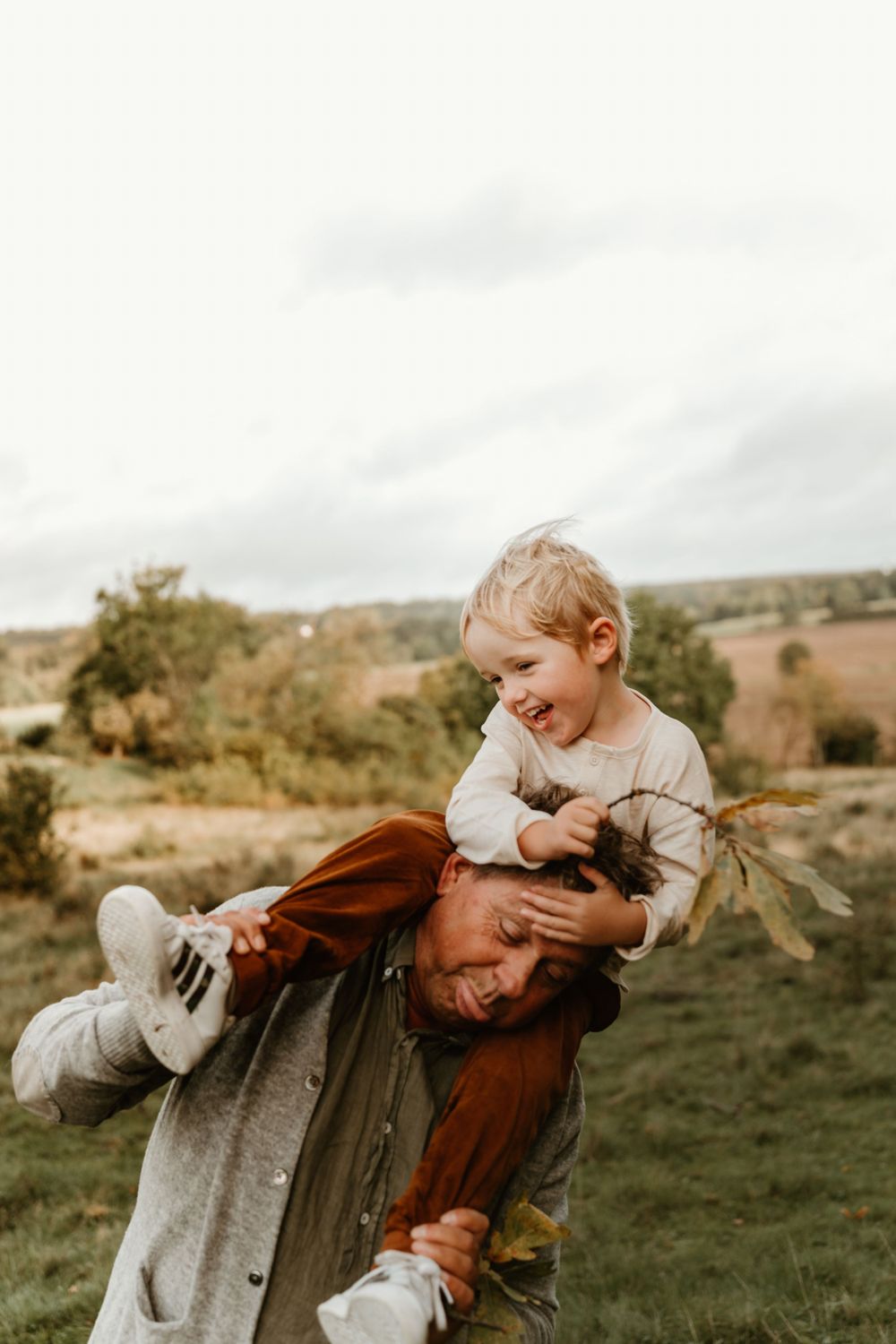 A joyful outdoor scene with someone being carried piggyback style against a rural landscape.
