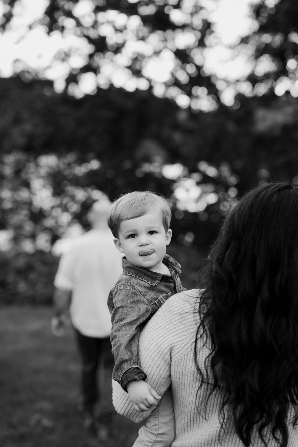 Black and white portrait of tender family interaction outdoors with bokeh background.
