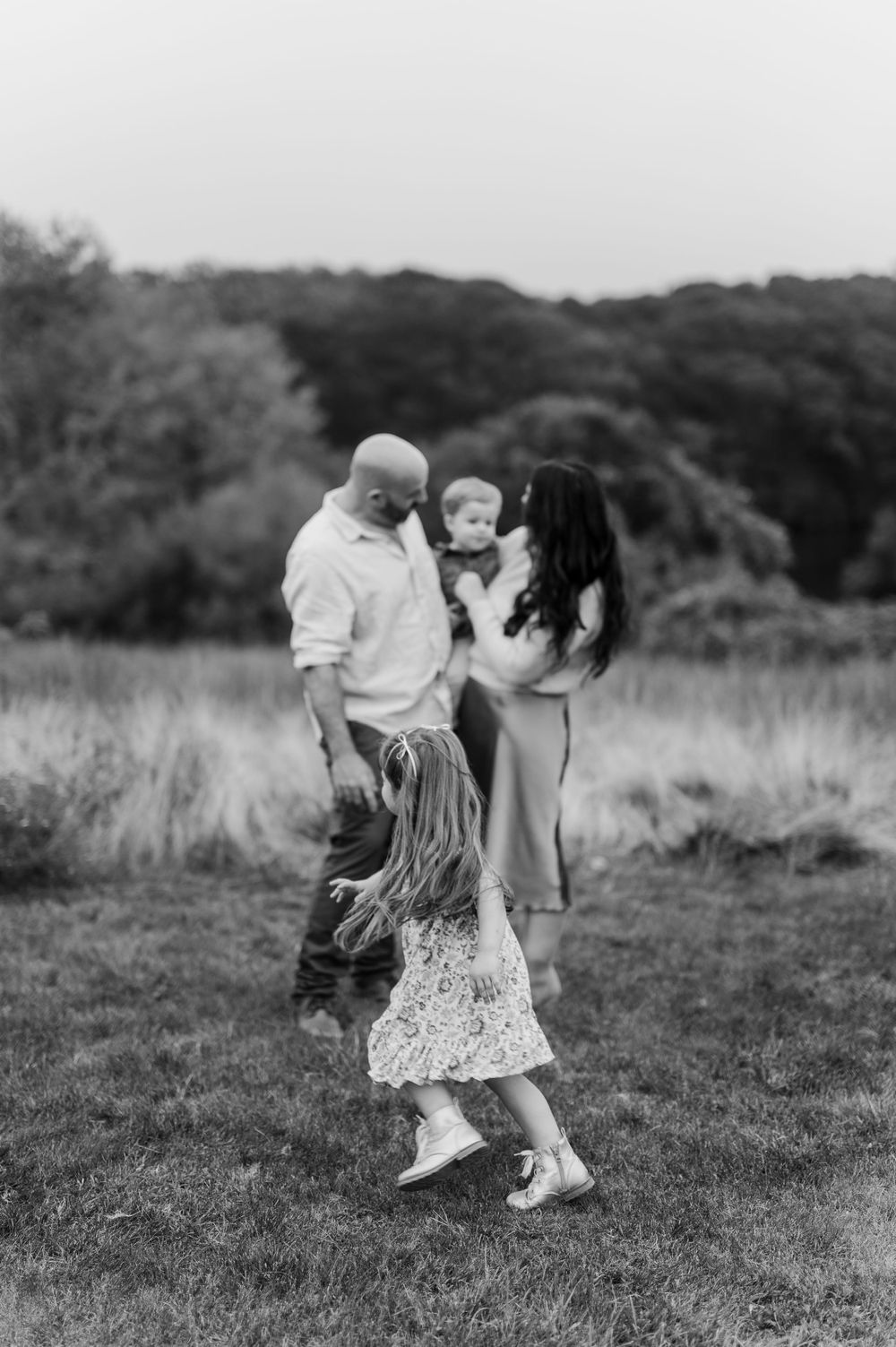 Black and white photo of a family playing together in a grassy meadow.