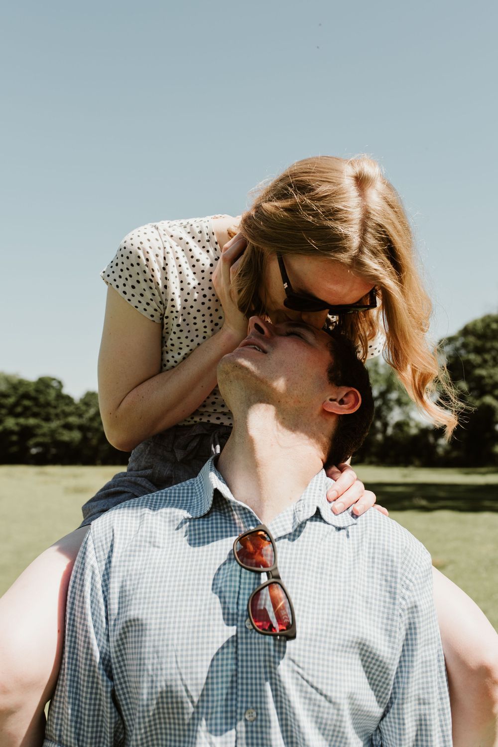 Romantic summer portrait of couple in polka dot dress and gingham shirt with sunglasses.