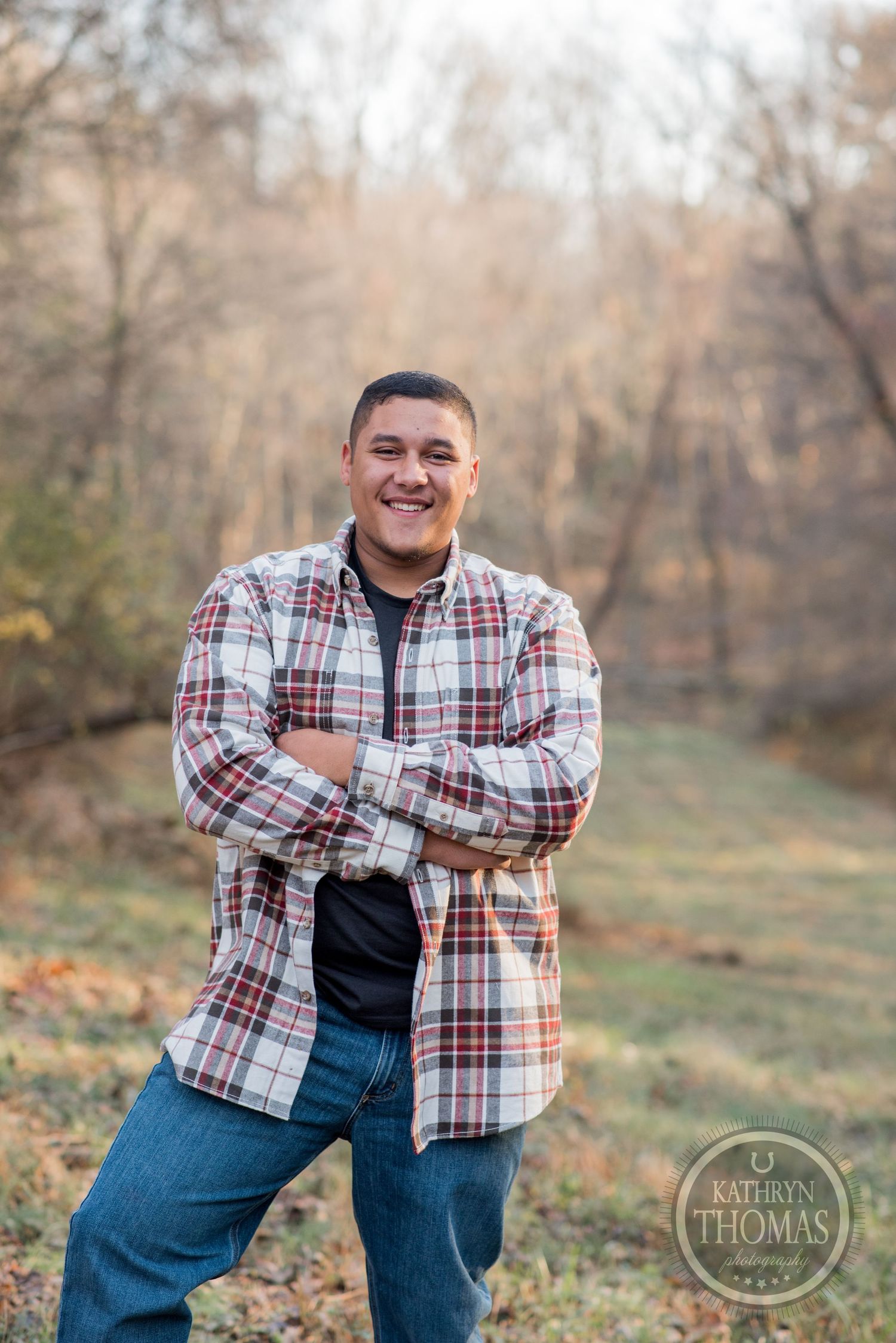 Cheerful portrait of someone in plaid flannel shirt against autumn woods background.