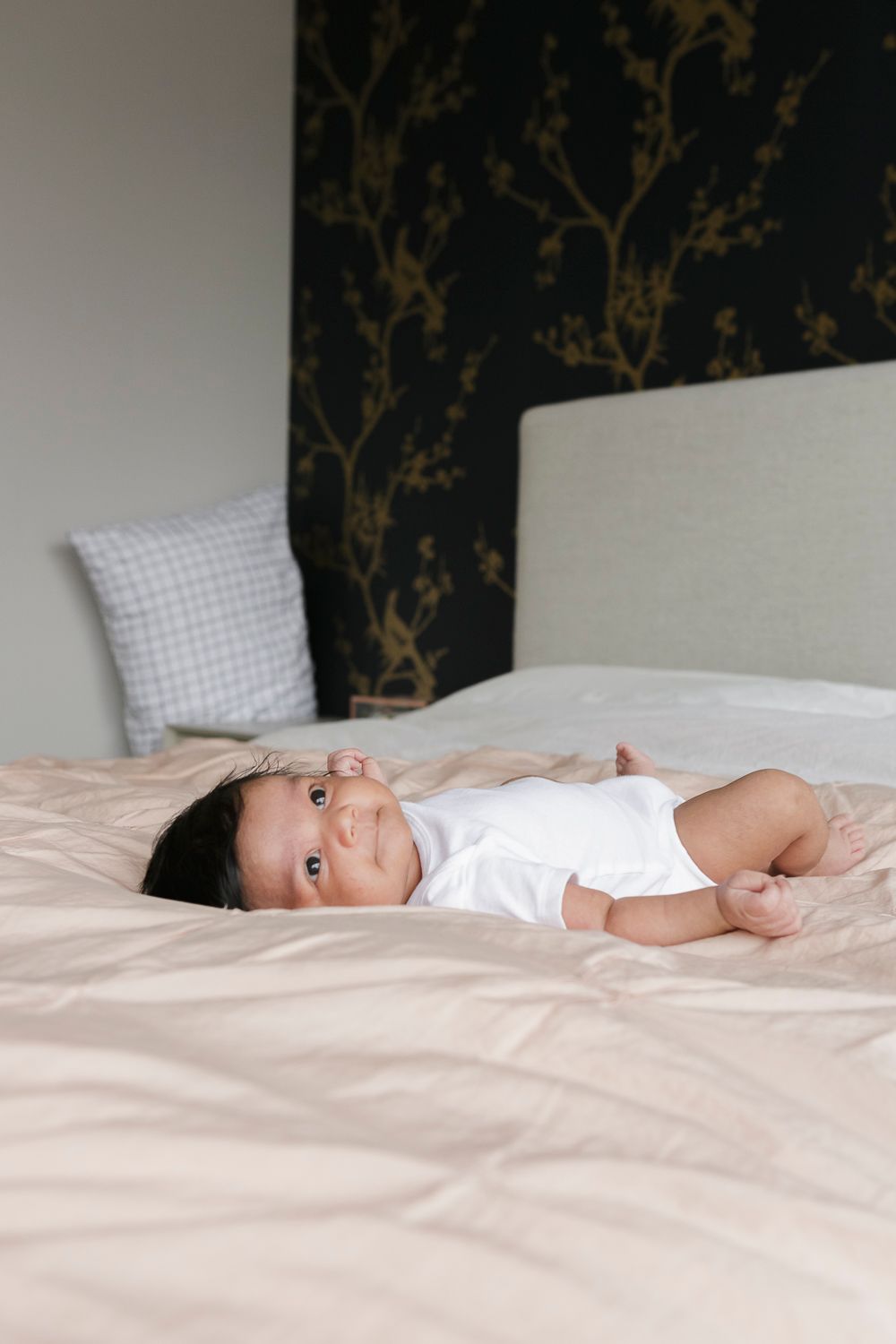 Newborn baby peacefully resting in bed, captured by NYC newborn photographer Paula Ortiz