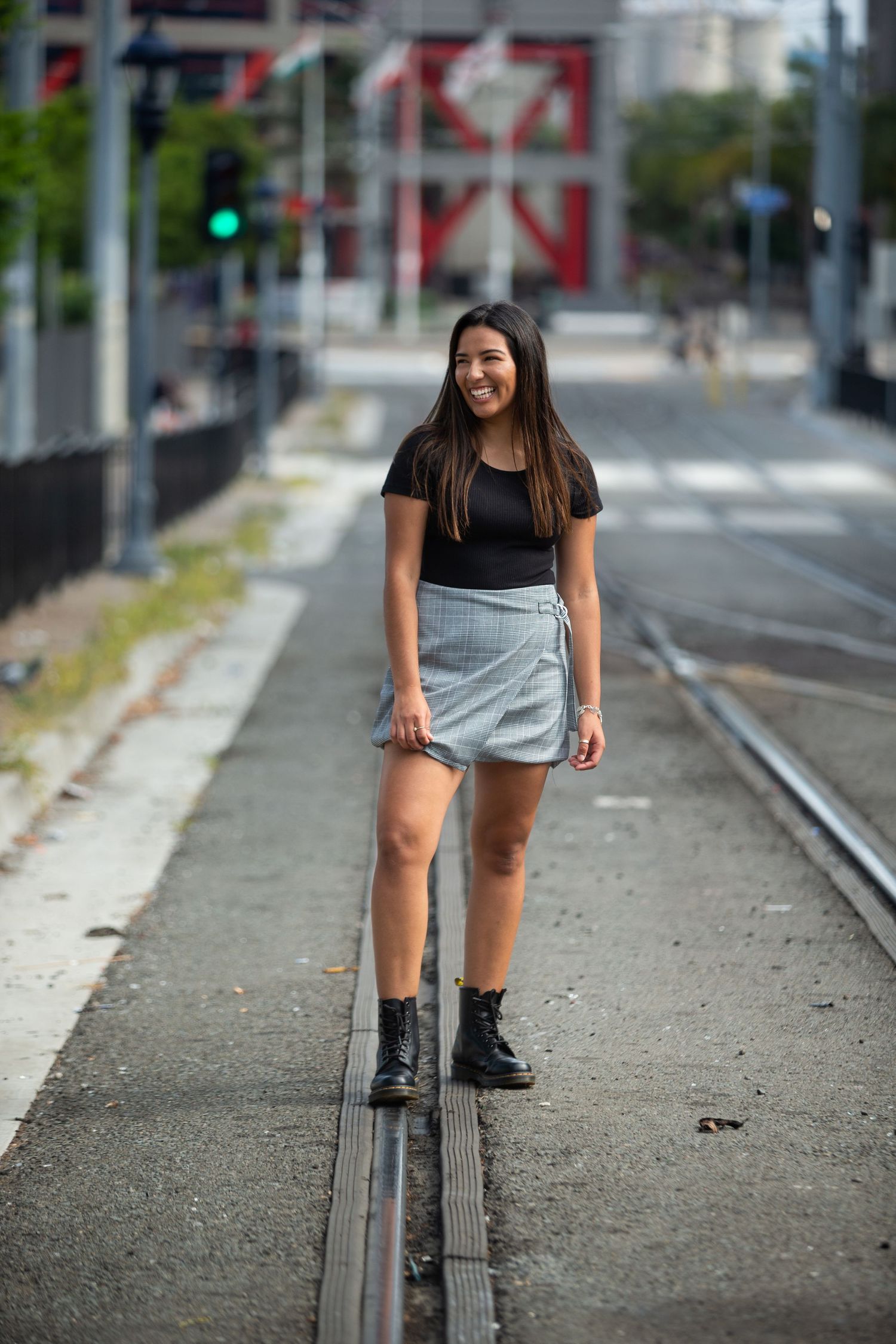 Urban portrait of someone standing on train tracks wearing a casual outfit with combat boots.