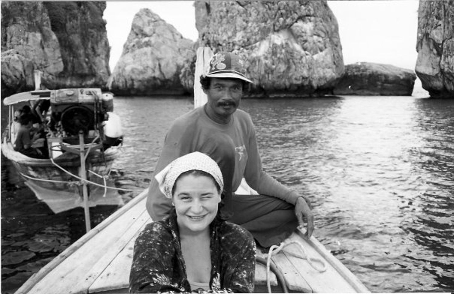 BW image of a boat driver with a young Kelly in front of him in his boat in Malaysia.