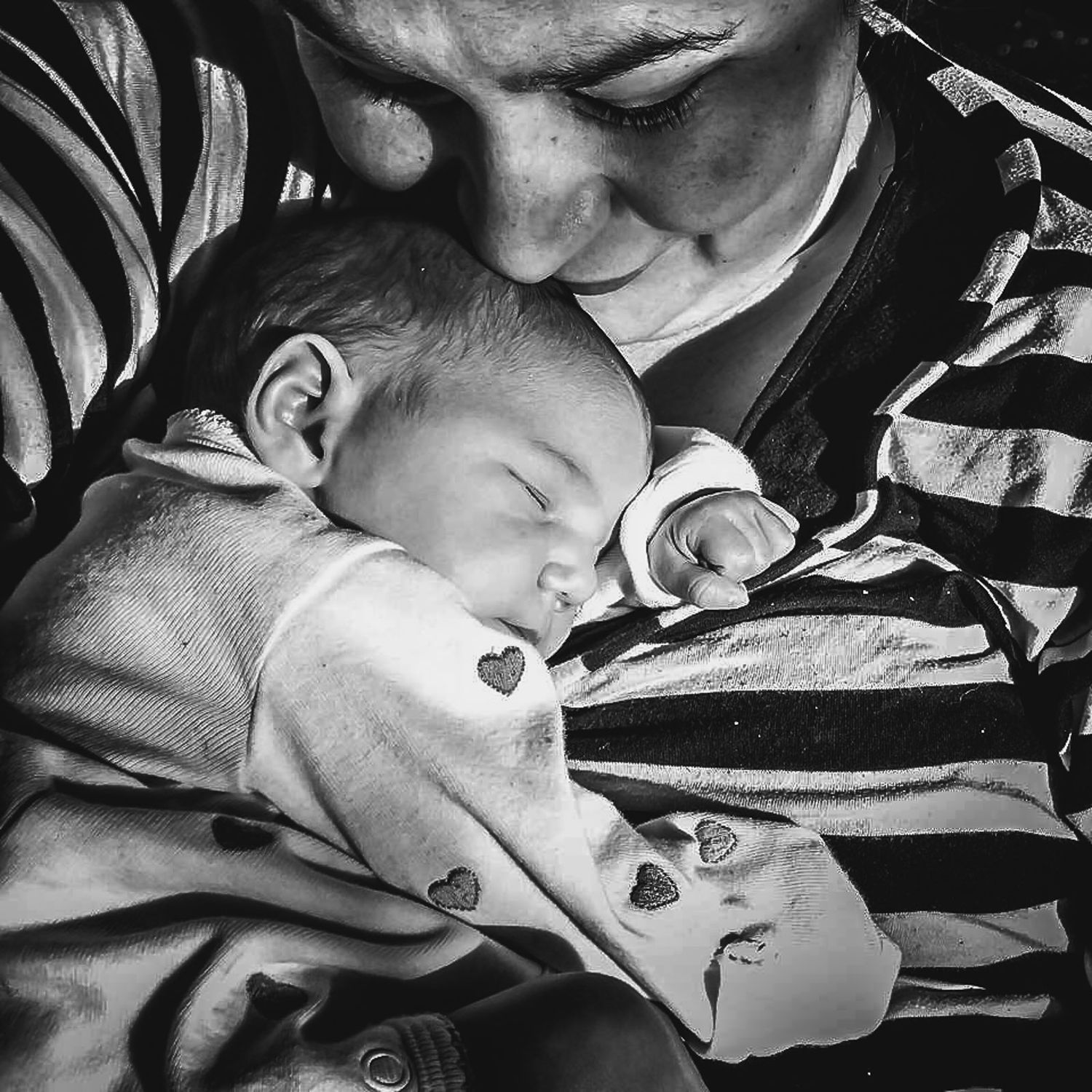 BW photo of a newborn being held by her mother.