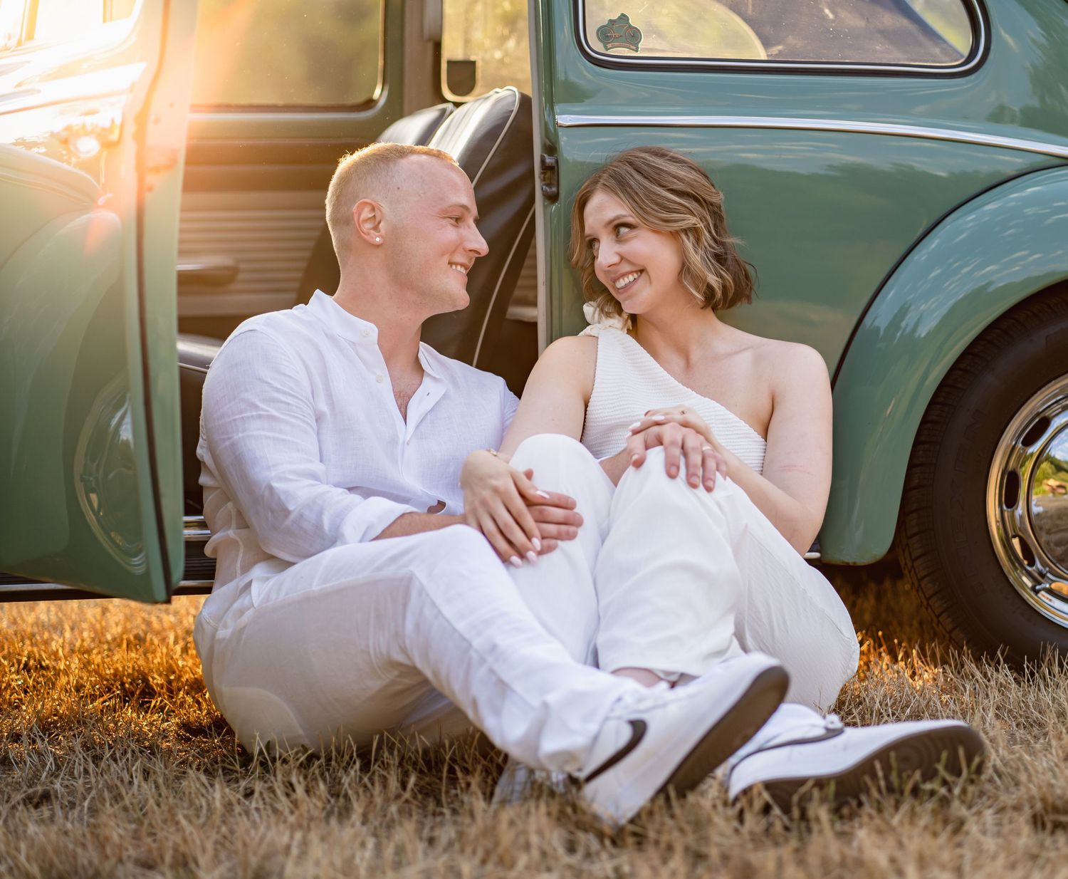 A romantic sunset portrait session with a vintage Volkswagen Beetle car in a golden field.