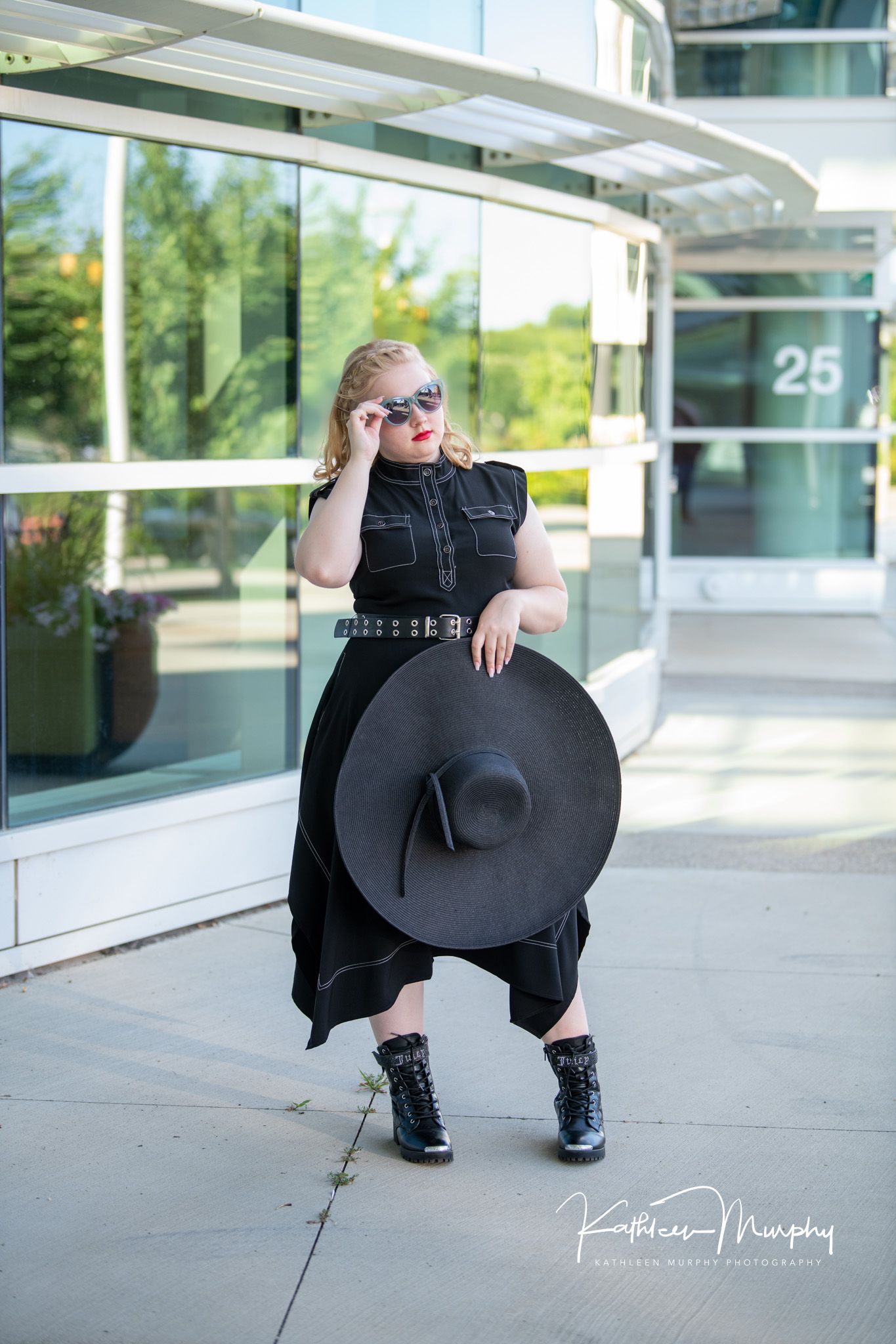 Kathleen Murphy Photography picture of a girl in a black dress holding a black floppy hat and wearing sunglasses