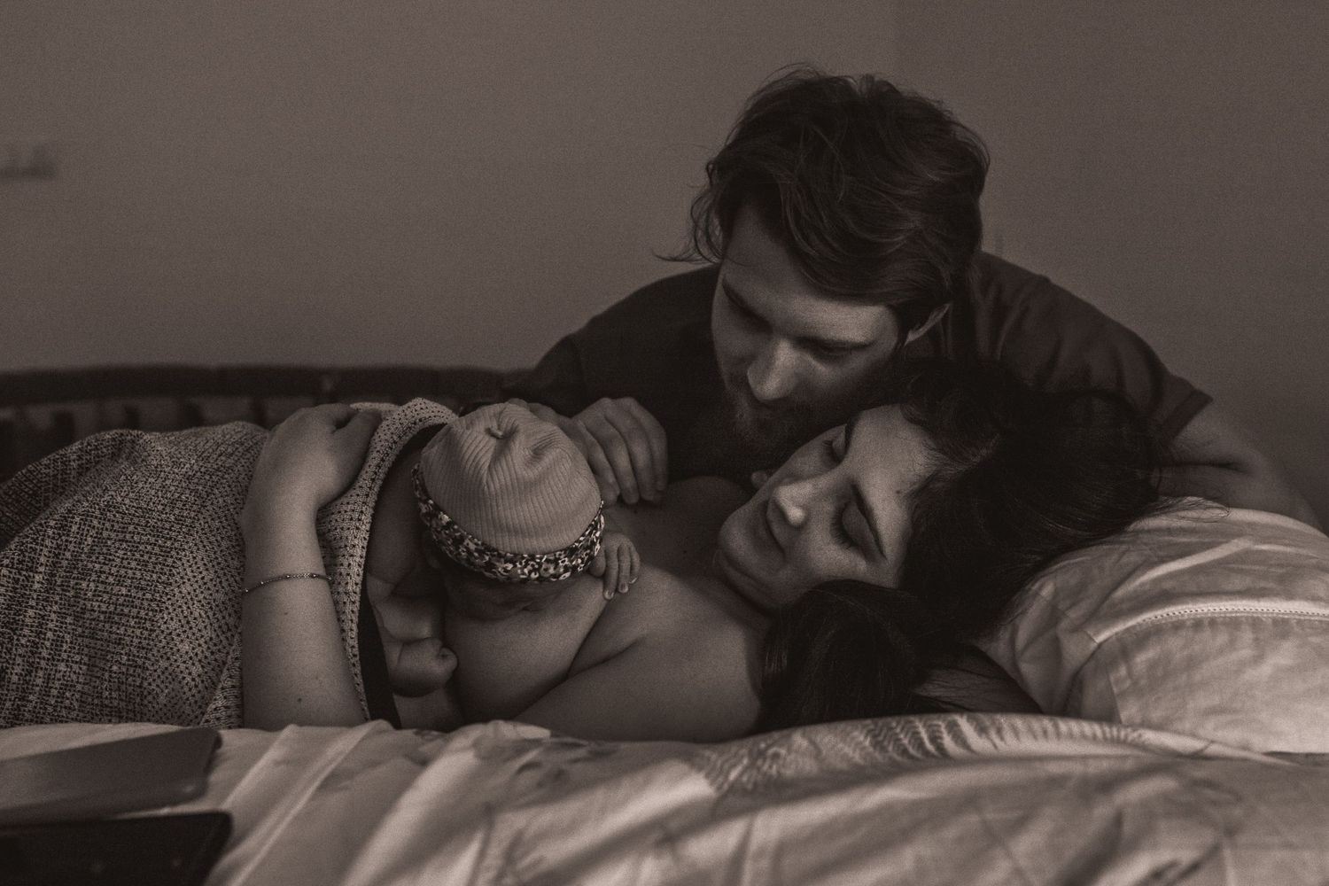 An intimate black and white photo of a family bonding with their newborn baby.