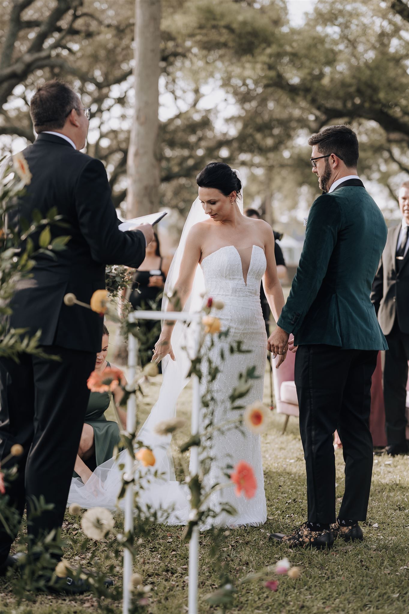 Outdoor wedding ceremony with delicate flower decorations and a couple in elegant attire.