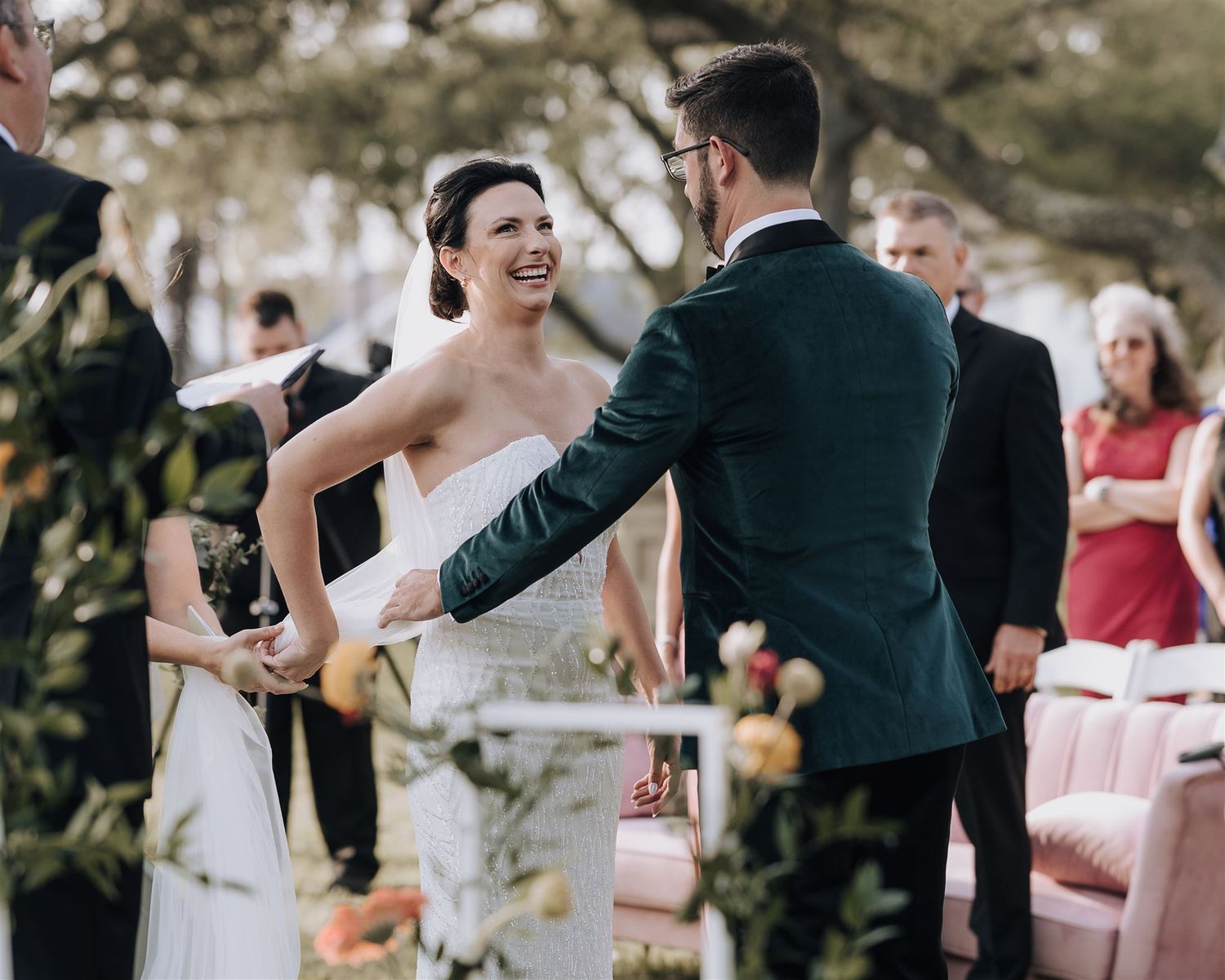 Joyful moment between couple during outdoor wedding ceremony with floral decorations.